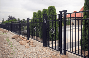 Sierlijk zwart metalen hekwerk met geïntegreerde poort als moderne tuinafsluiting, geplaatst voor een woning met strakke tuinopbouw