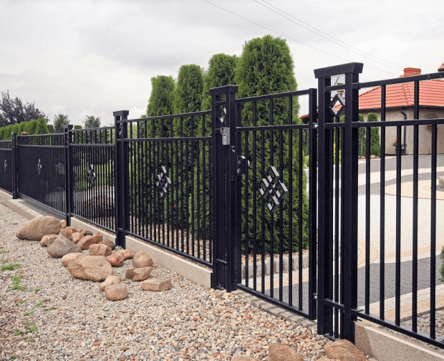 Sierlijk zwart metalen hekwerk met geïntegreerde poort als moderne tuinafsluiting, geplaatst voor een woning met strakke tuinopbouw