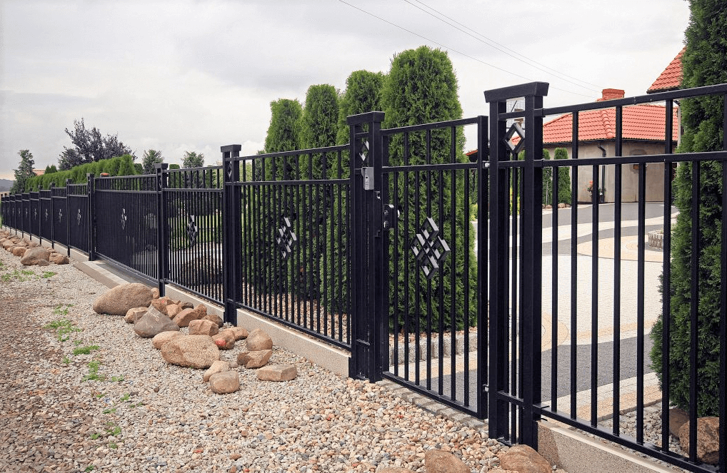 Sierlijk zwart metalen hekwerk met geïntegreerde poort als moderne tuinafsluiting, geplaatst voor een woning met strakke tuinopbouw