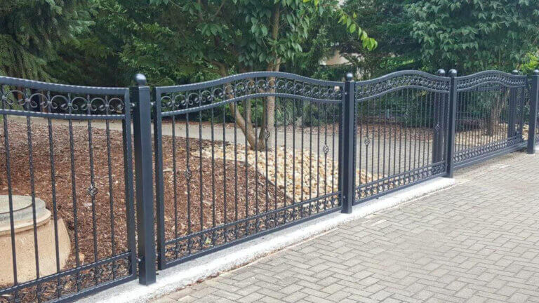 Klassiek zwart sierhekwerk met sierbogen en decoratieve elementen als voortuin hek idee
